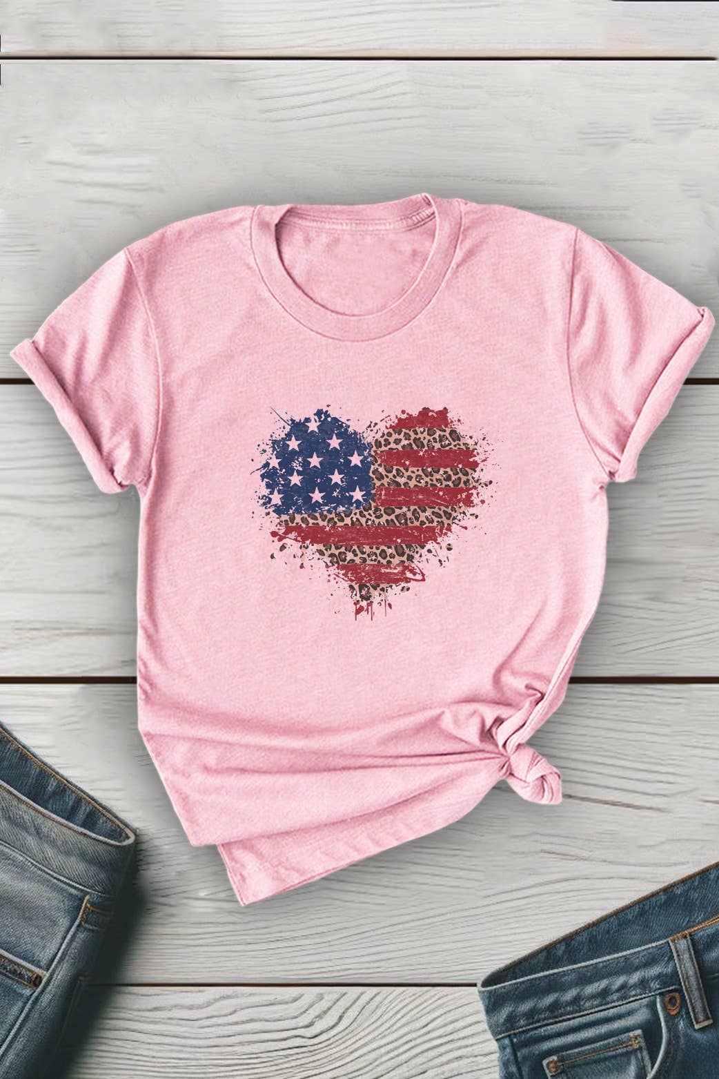 Pink t-shirt with a heart-shaped American flag design on a wooden surface.