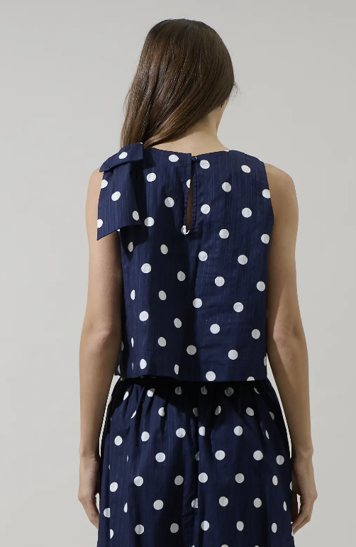 Navy blue skirt with white polka dots worn by a person on a plain background
