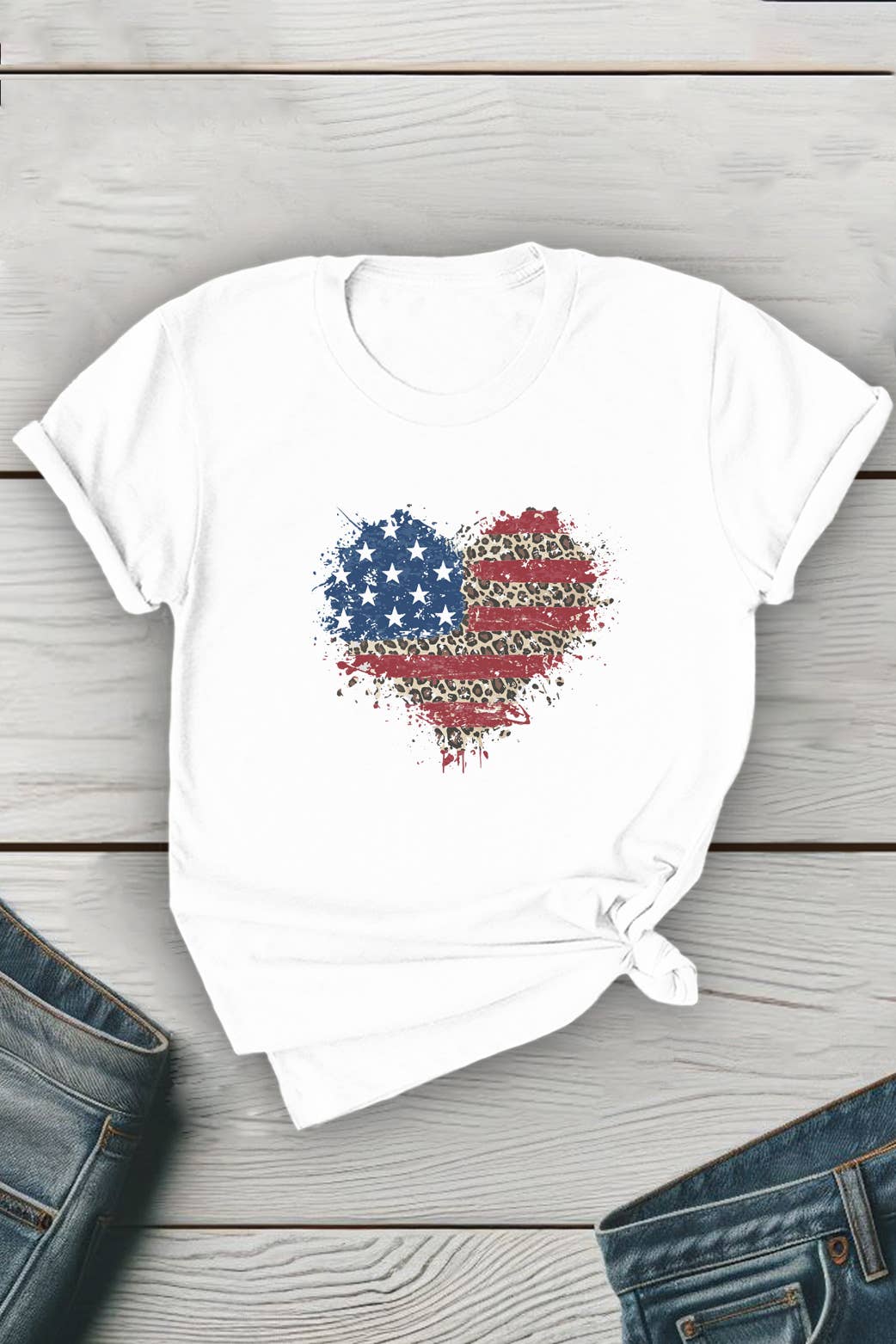 White t-shirt with a heart-shaped American flag design on a wooden surface.