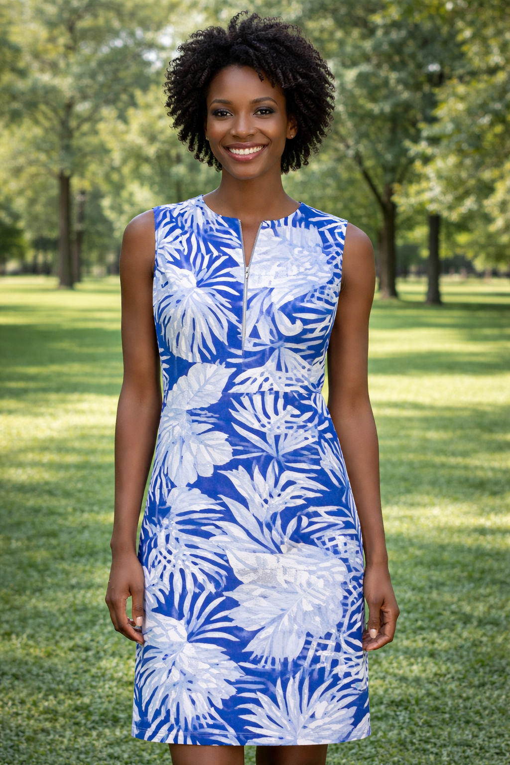 Woman wearing a blue and white floral dress standing in a park.