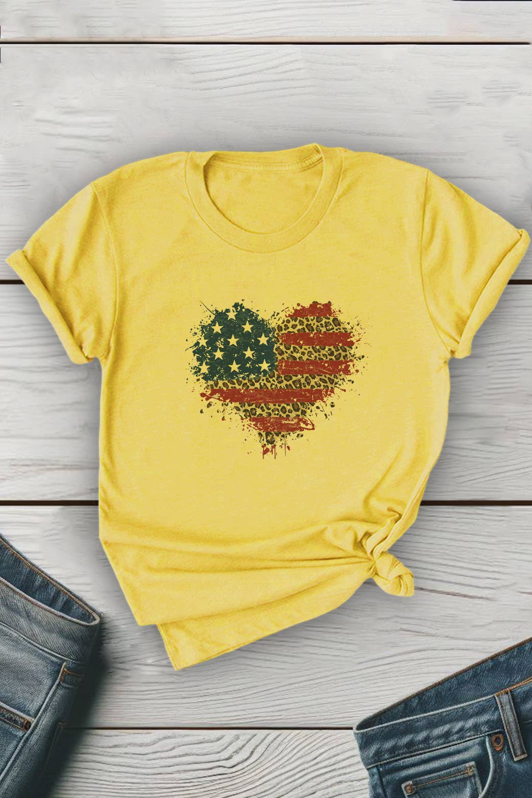 Yellow t-shirt with a heart-shaped American flag design on a wooden surface.