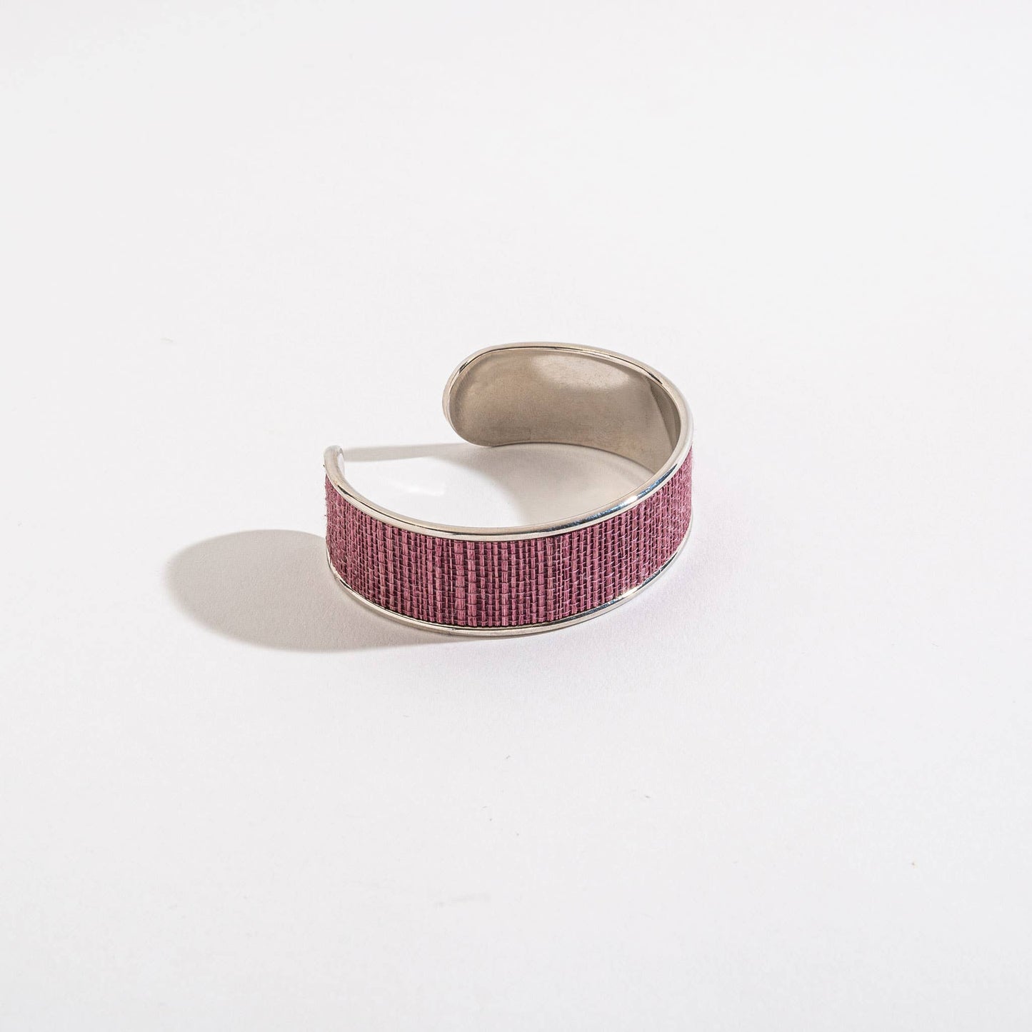 Silver cuff bracelet with a pink textured band on a white background