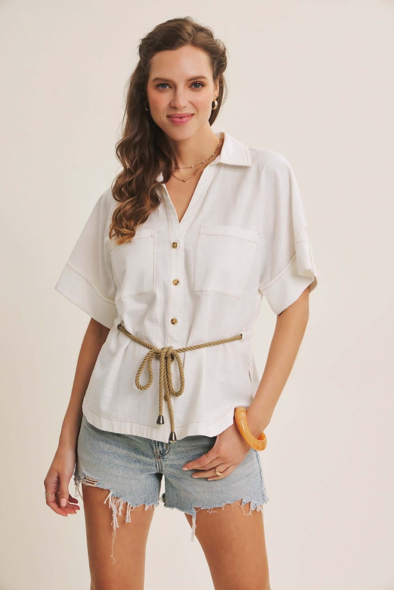 Woman wearing a white shirt and denim shorts on a plain background