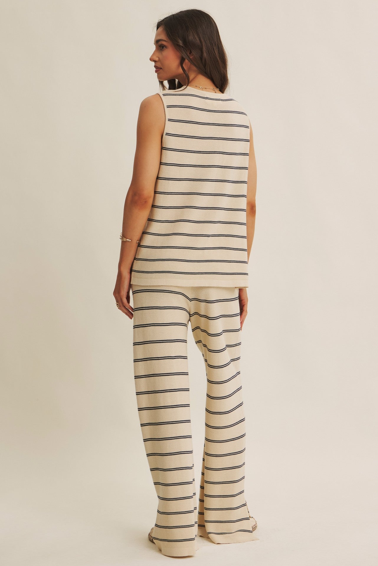 Woman wearing a striped sleeveless top and pants on a beige background