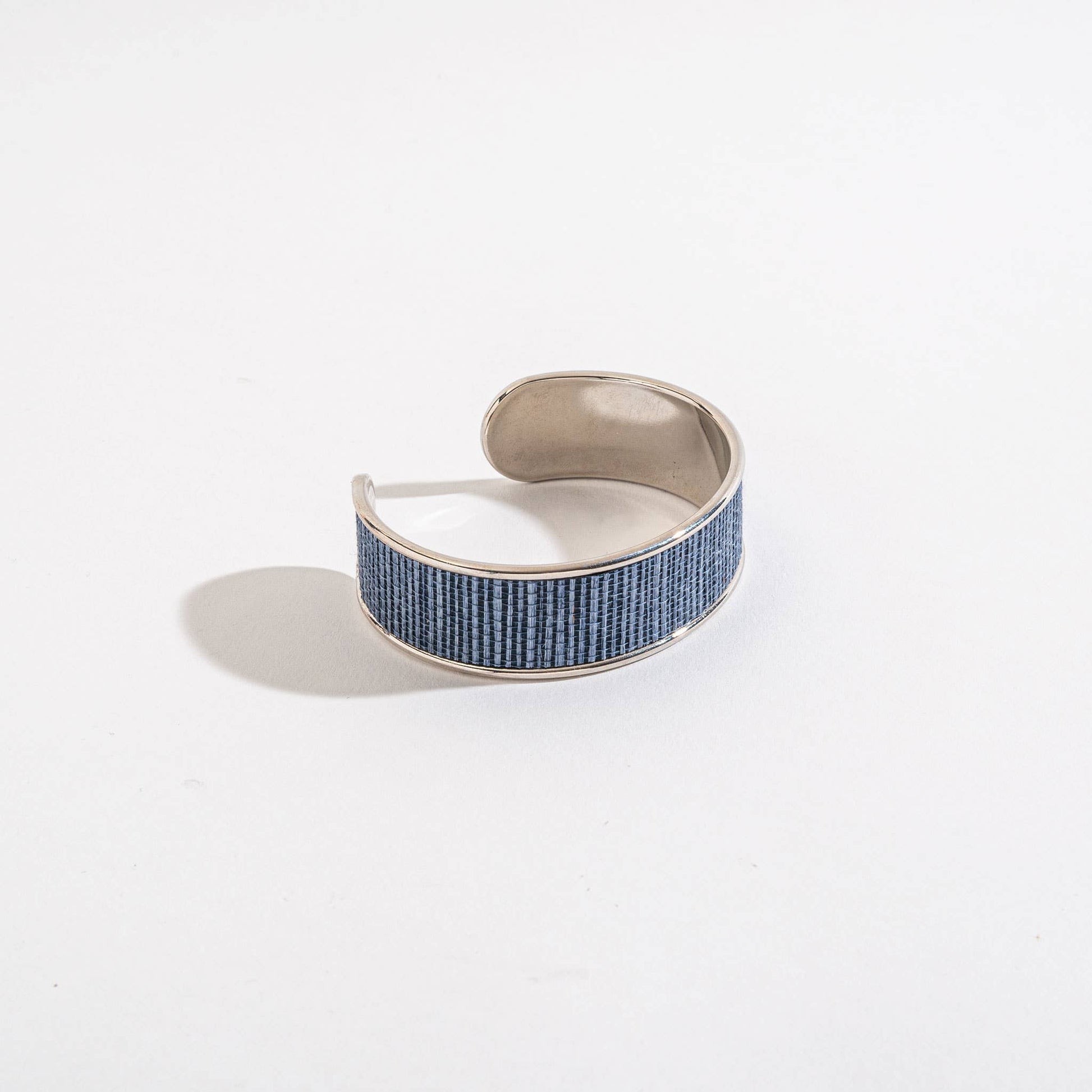 Silver cuff bracelet with blue pattern on a white background