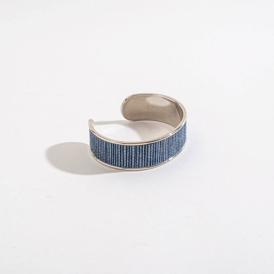 Silver cuff bracelet with blue pattern on a white background