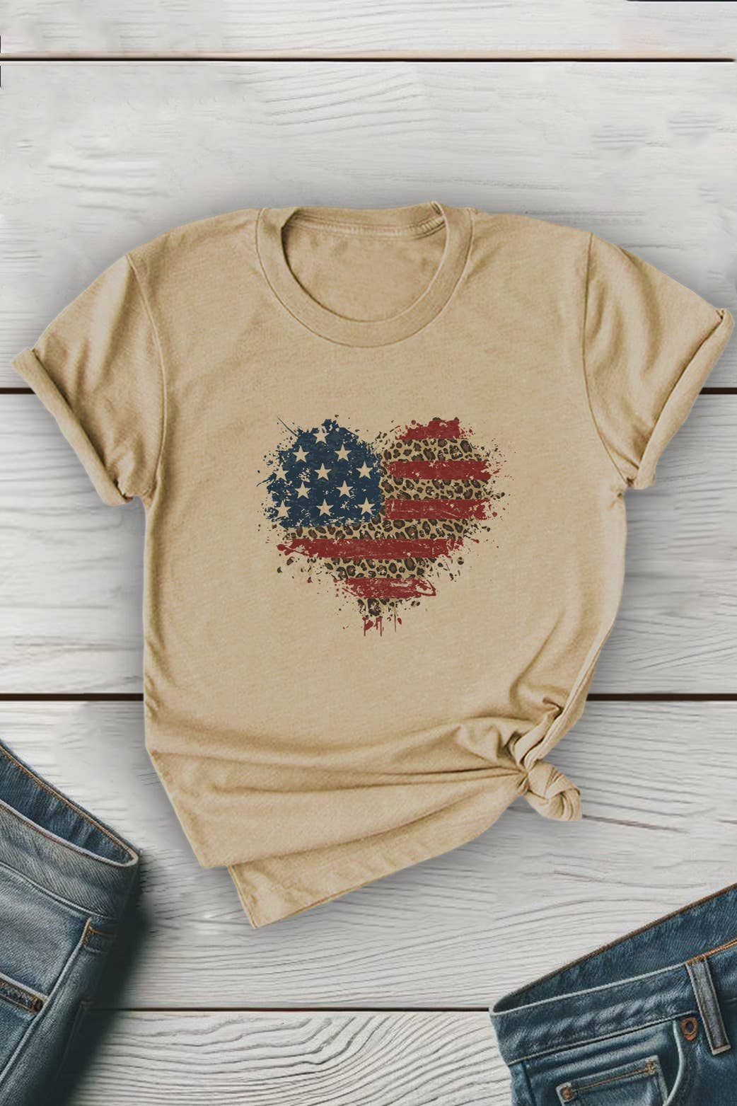 Beige t-shirt with a heart-shaped American flag design on a wooden surface with jeans.
