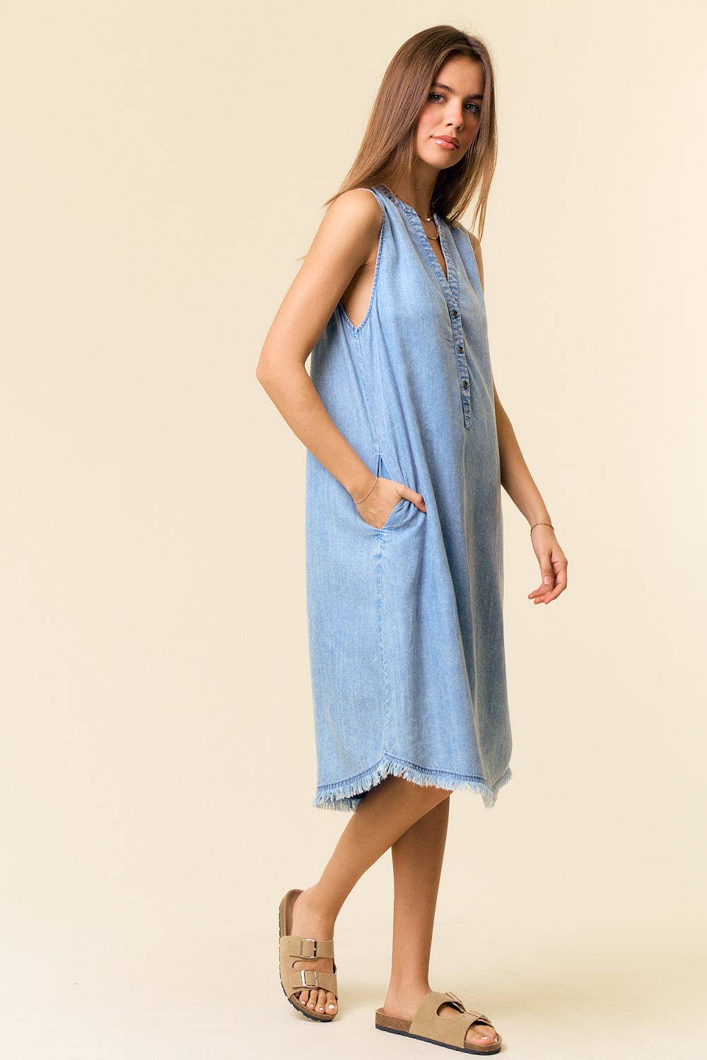 Woman wearing a light blue sleeveless dress on a beige background