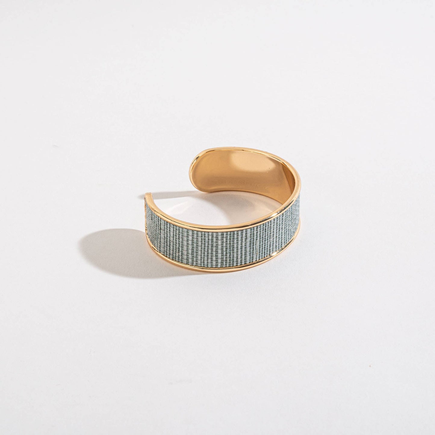 Gold and textured green bracelet on a light gray background