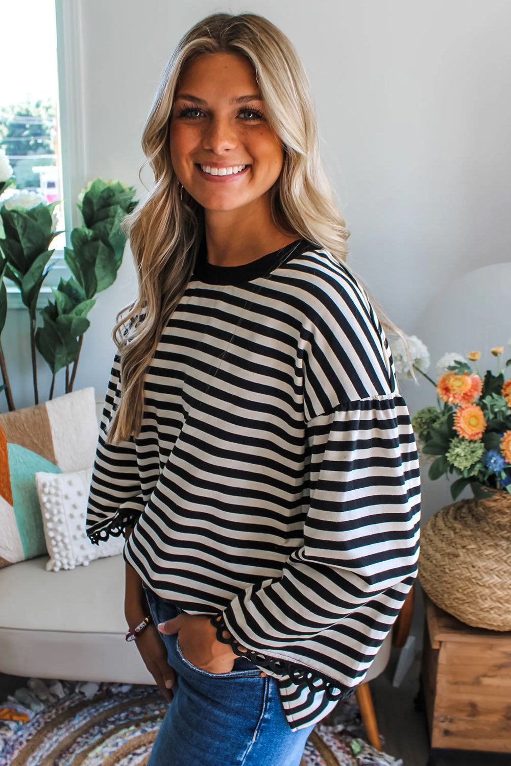 Woman wearing a black and white striped sweater in a cozy living room.