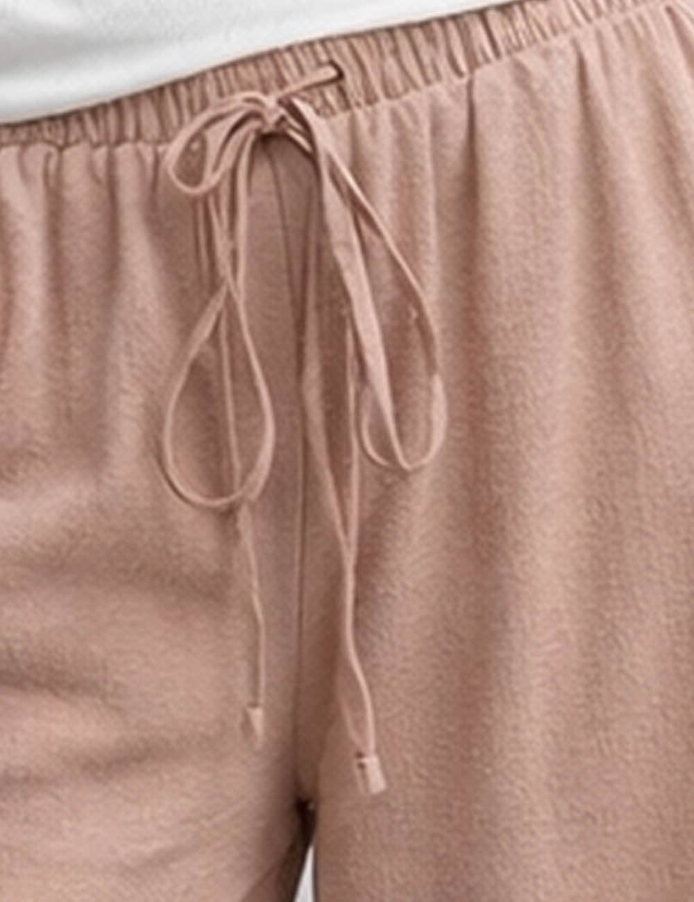 Close-up of beige drawstring pants with a white shirt underneath.
