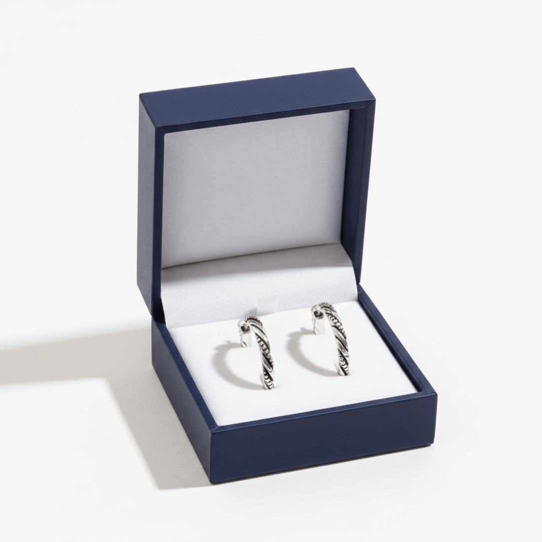 Pair of silver hoop earrings in an open blue jewelry box on a white background