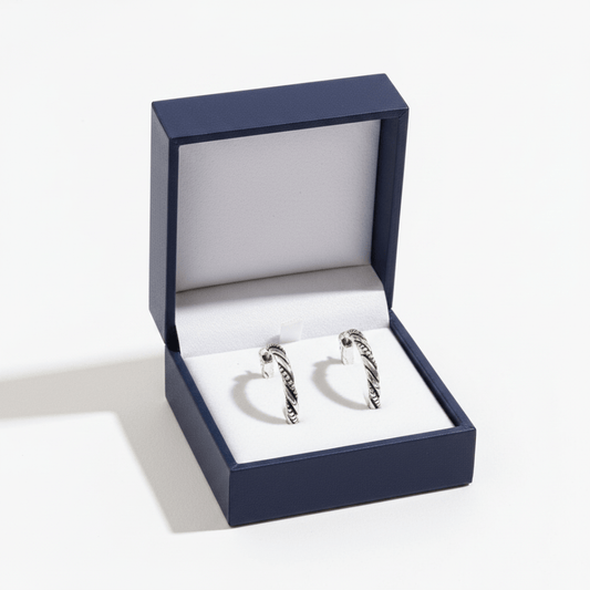 Pair of silver hoop earrings in an open blue jewelry box on a white background