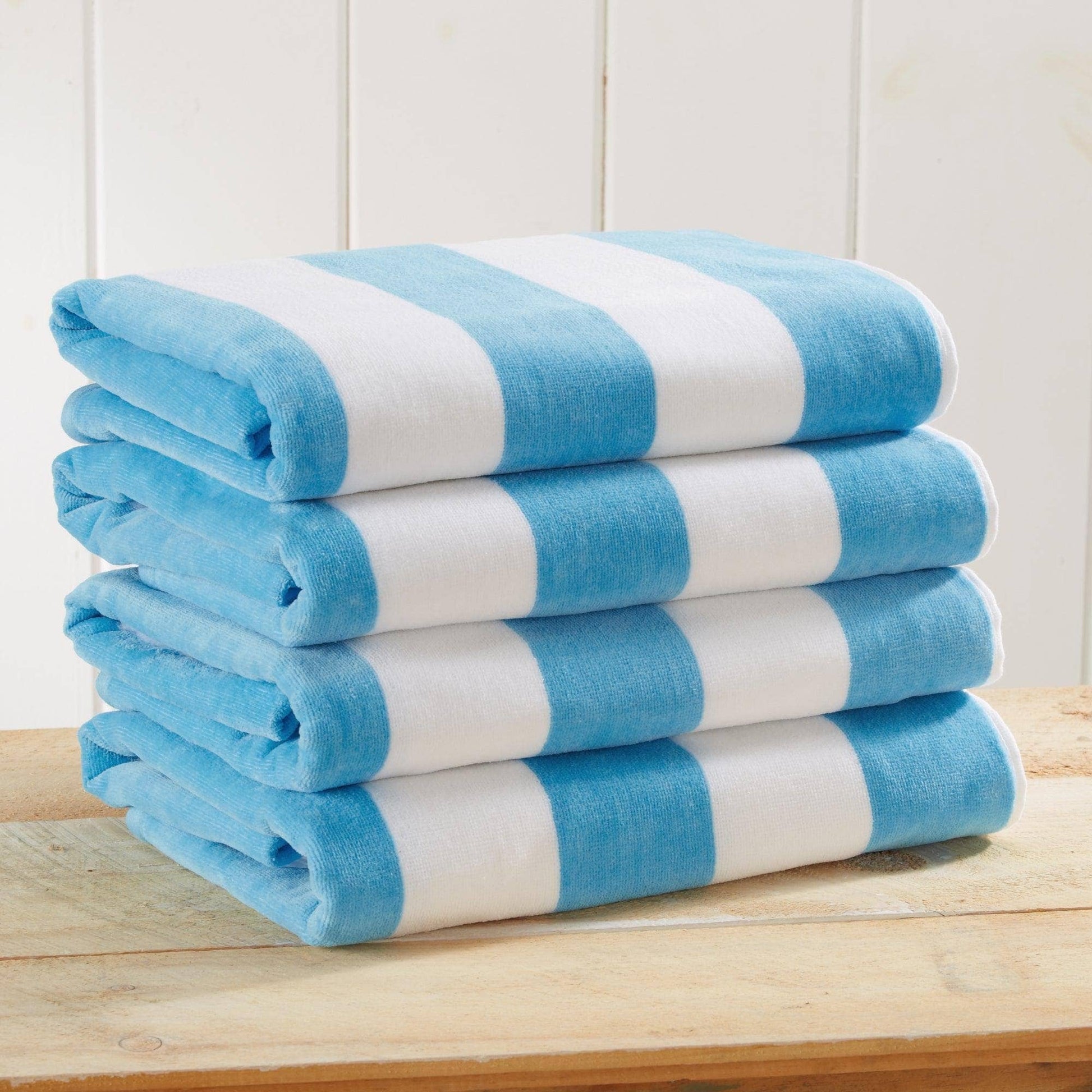 Stack of blue and white striped towels on a wooden surface with a white paneled wall background.