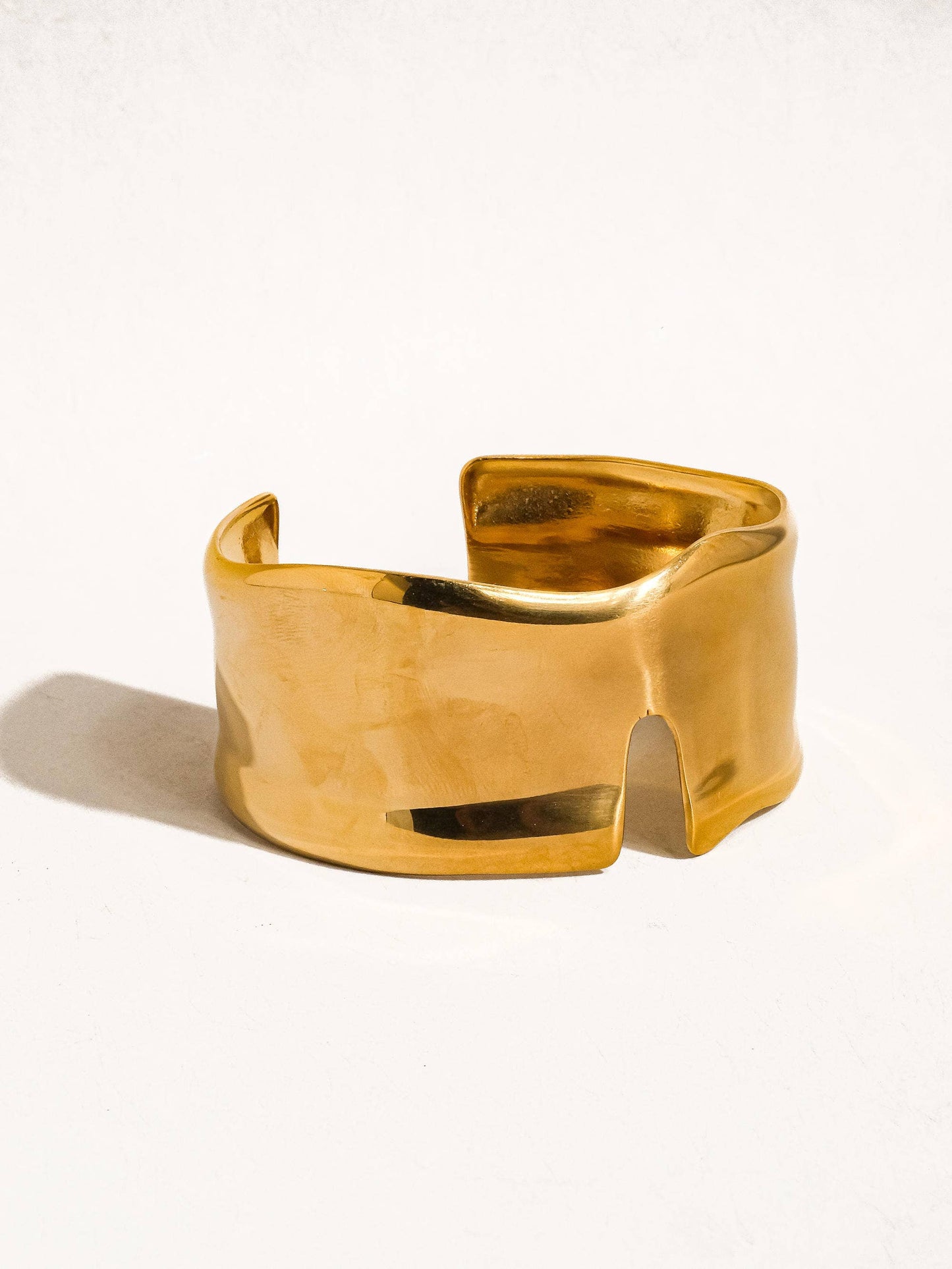 Gold cuff bracelet on a white background