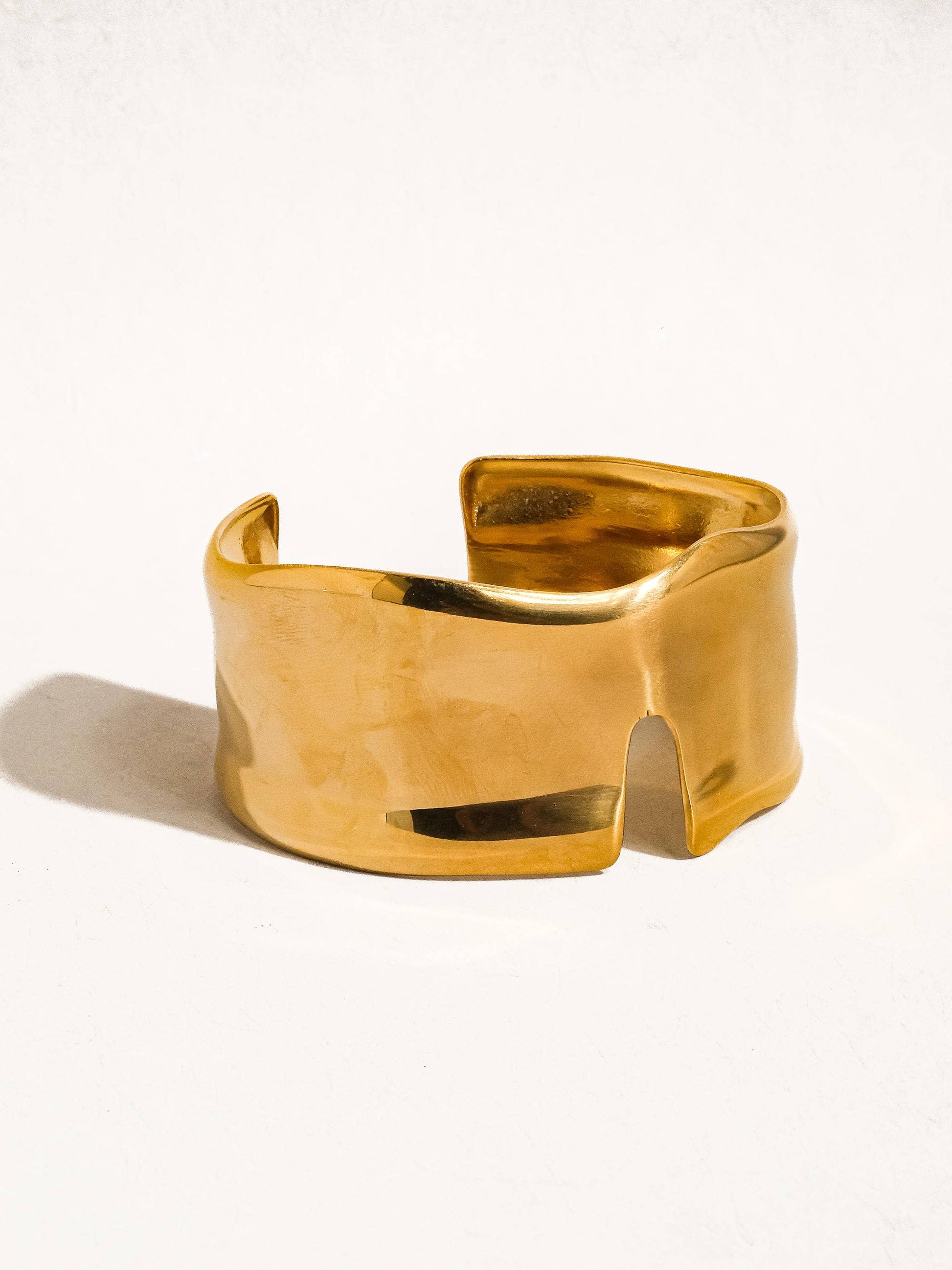 Gold cuff bracelet on a white background