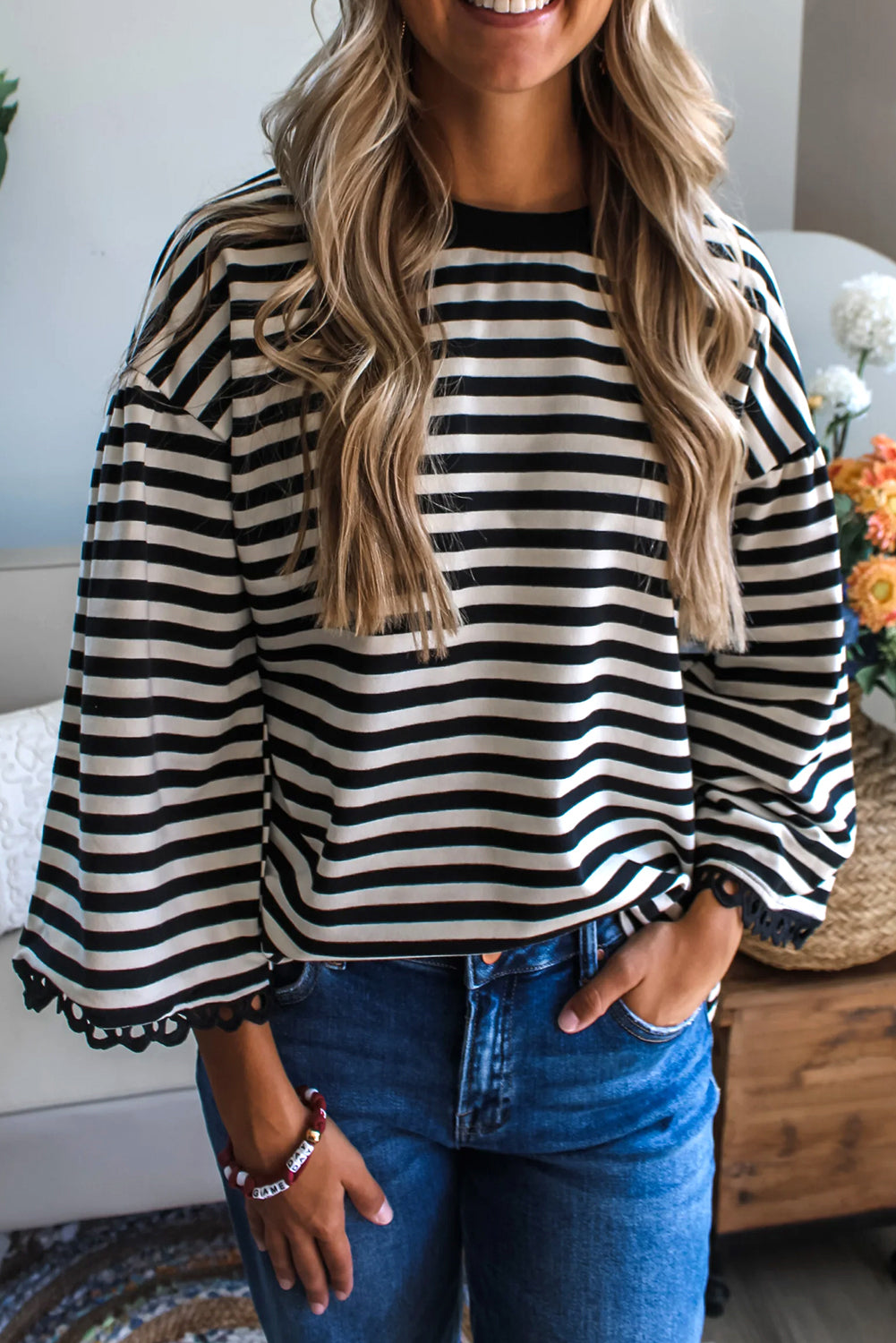 Woman wearing a black and white striped shirt with blue jeans indoors.