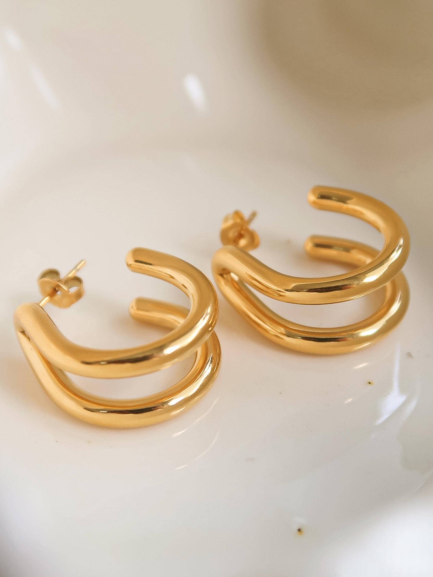 Gold hoop earrings on a white dish