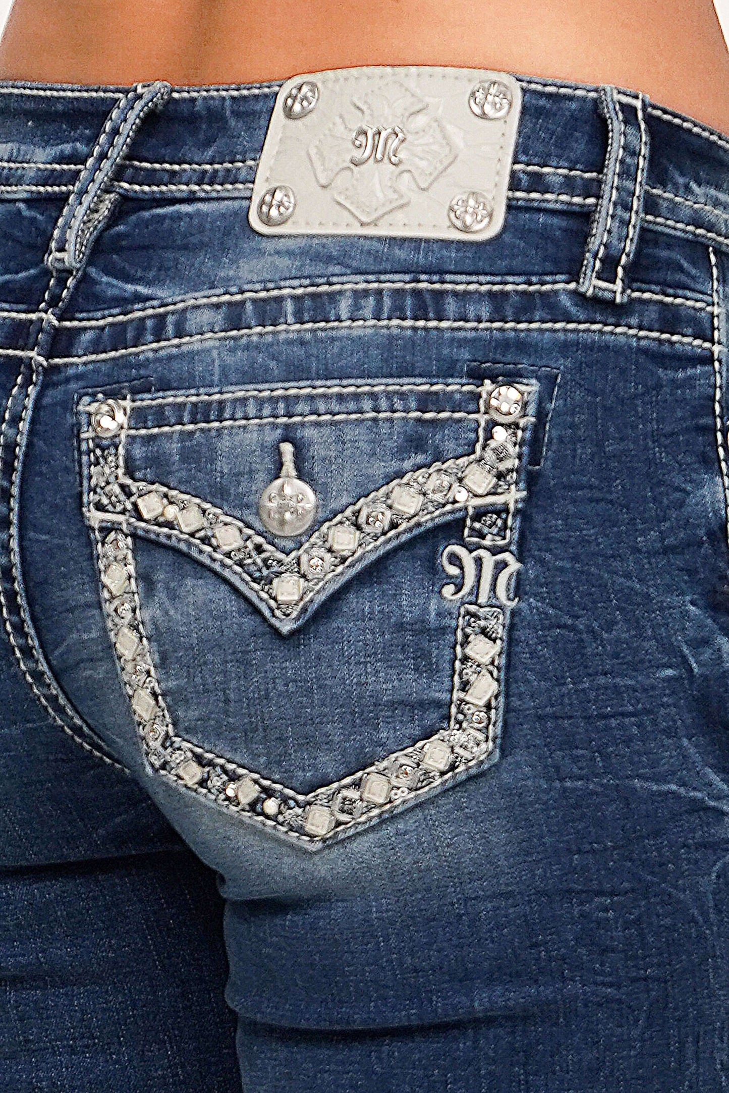 Close-up of blue jeans with decorative embellishments and a brand logo.
