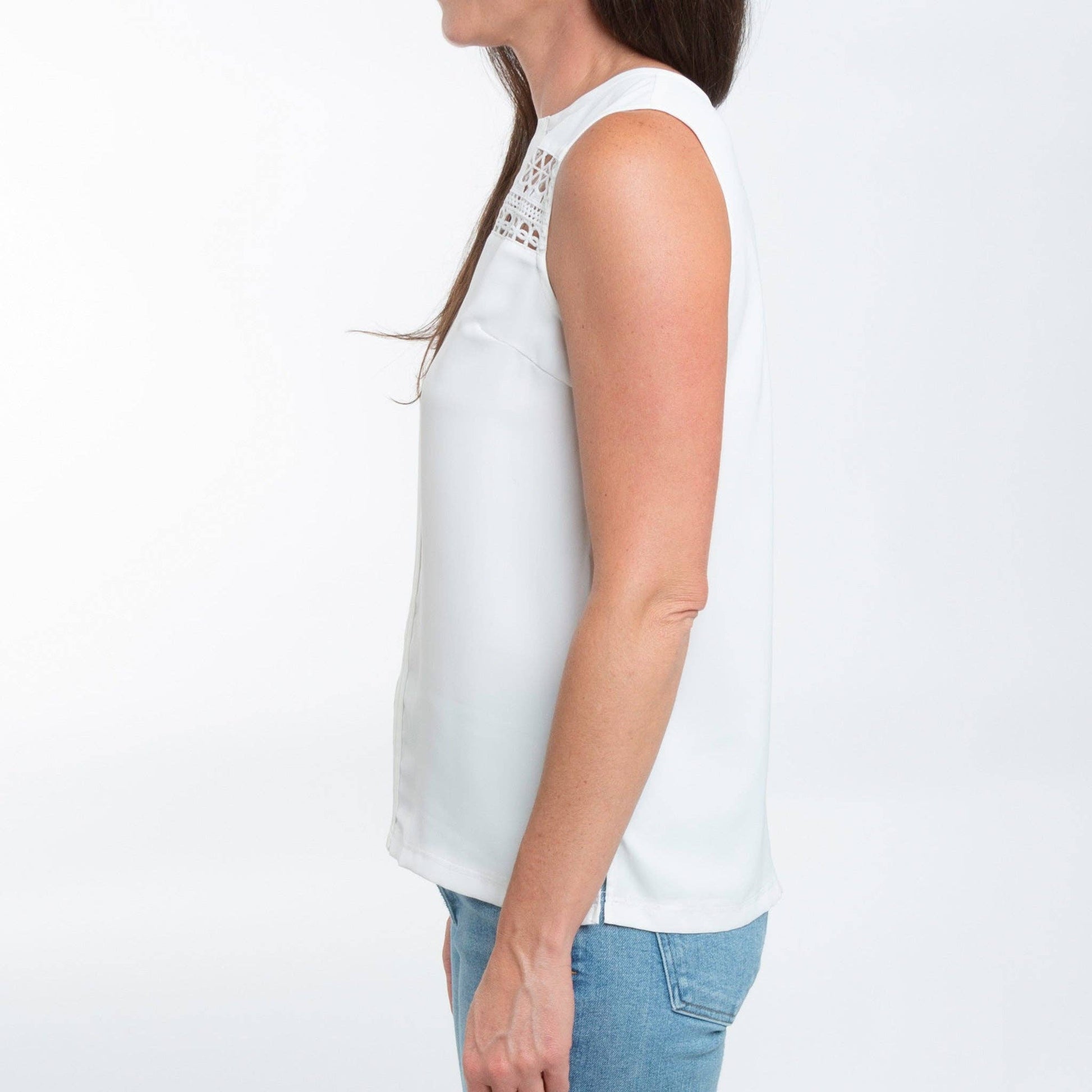 White sleeveless top with lace details worn by a person on a white background