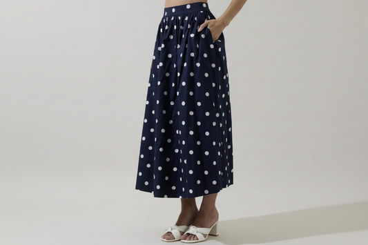 Navy blue skirt with white polka dots worn by a person on a plain background