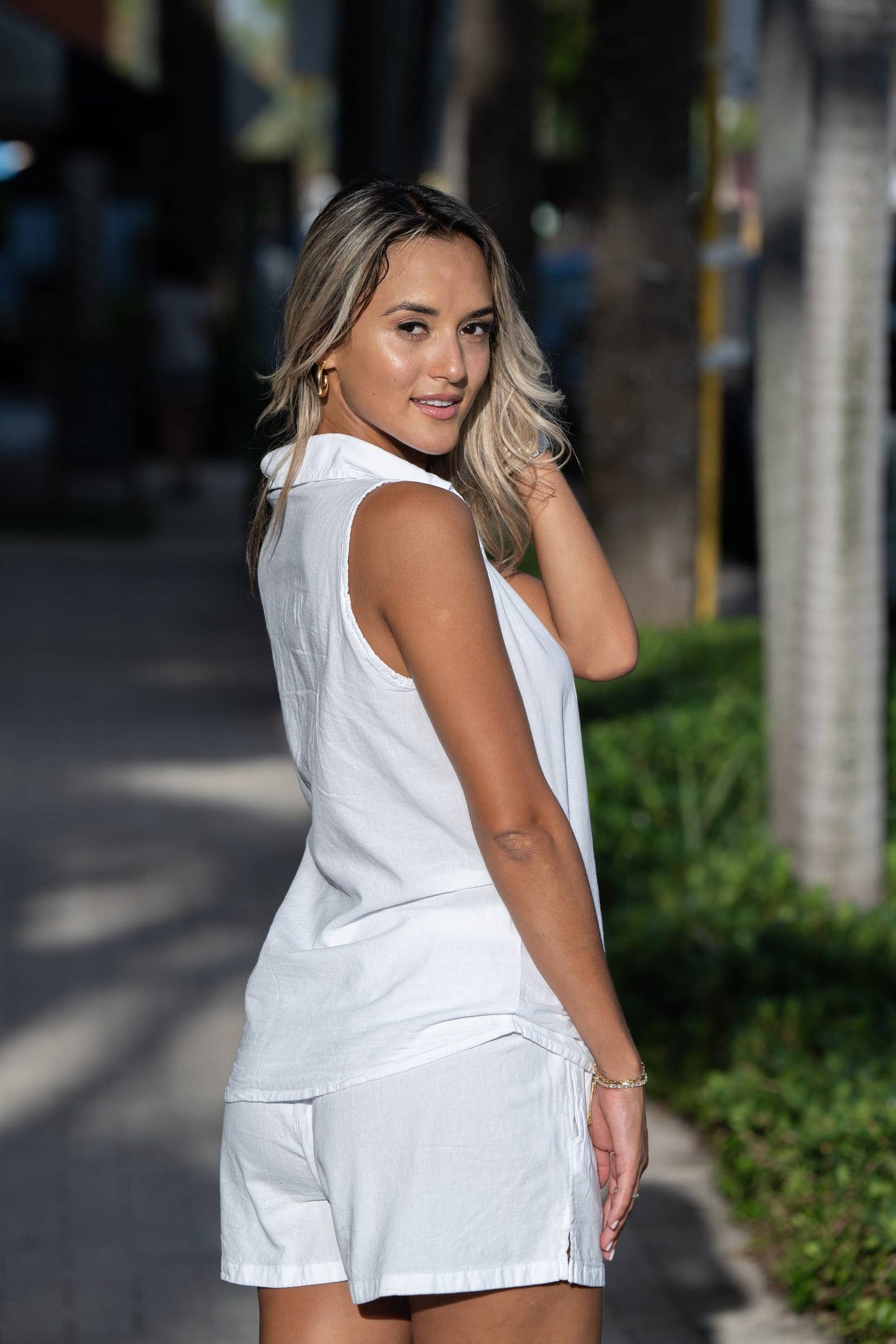 Woman in a white outfit standing on a street with blurred background