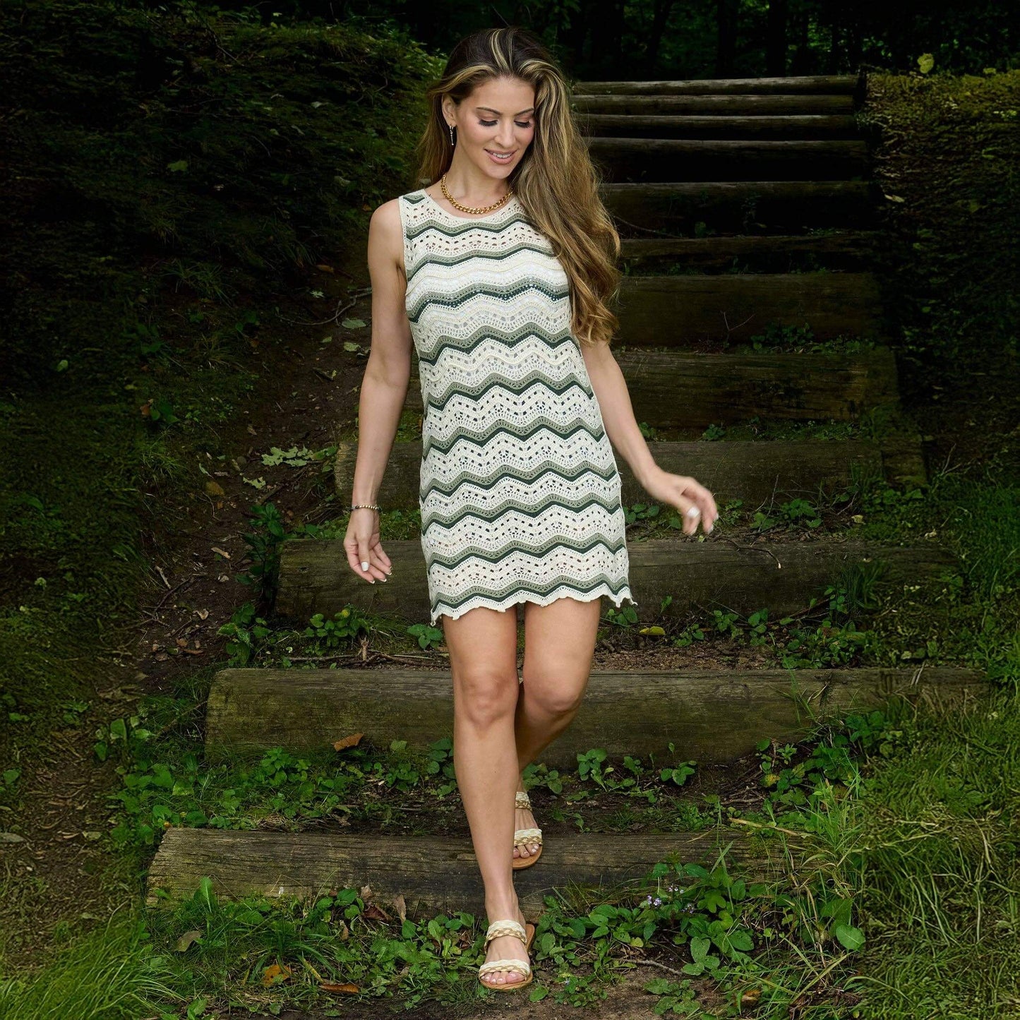 Woman in a patterned dress walking on wooden steps in a natural setting