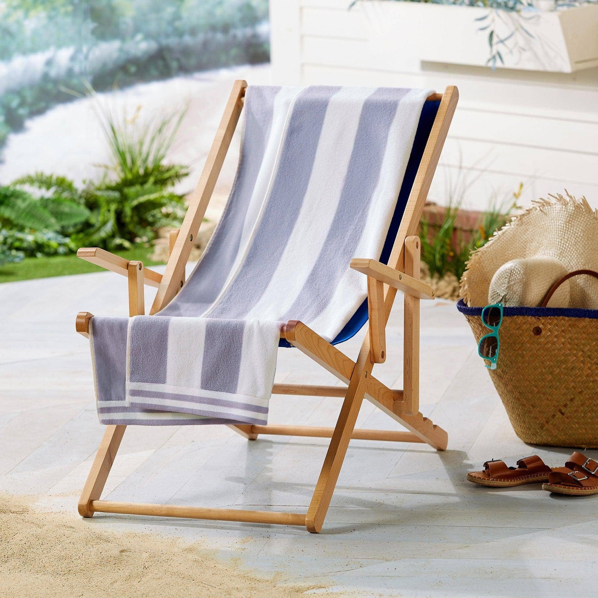 Wooden deck chair with a striped towel on a patio