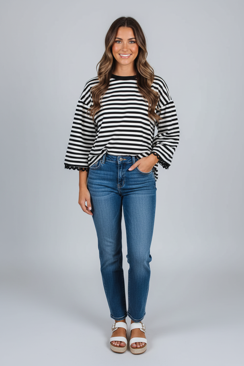 Woman wearing a black and white striped sweater and blue jeans on a gray background