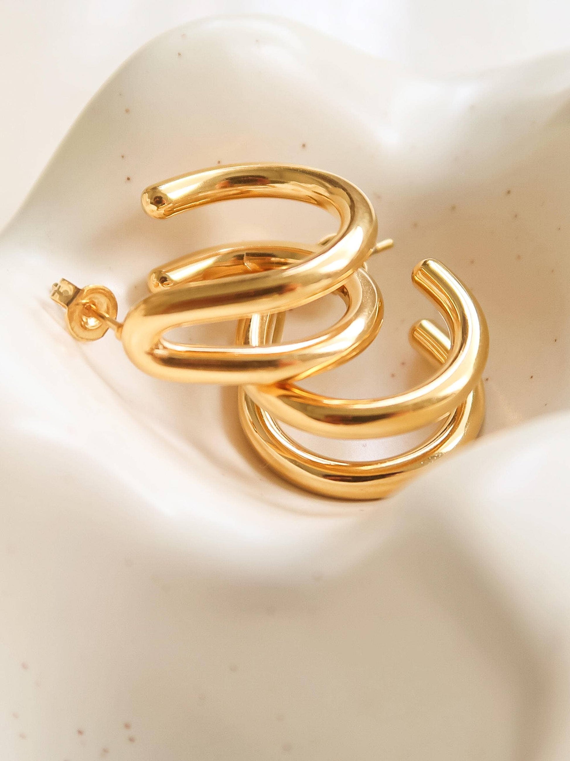 Gold hoop earrings on a beige surface