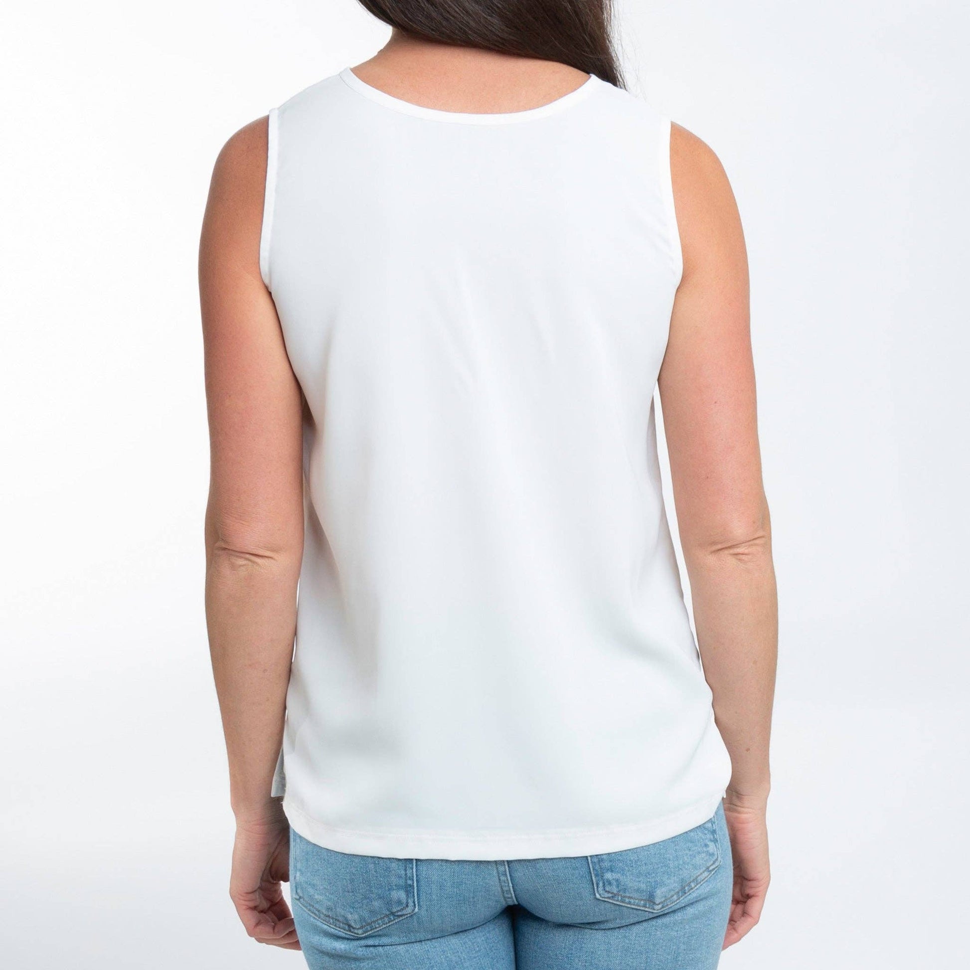 Person wearing a white sleeveless top and blue jeans on a white background
