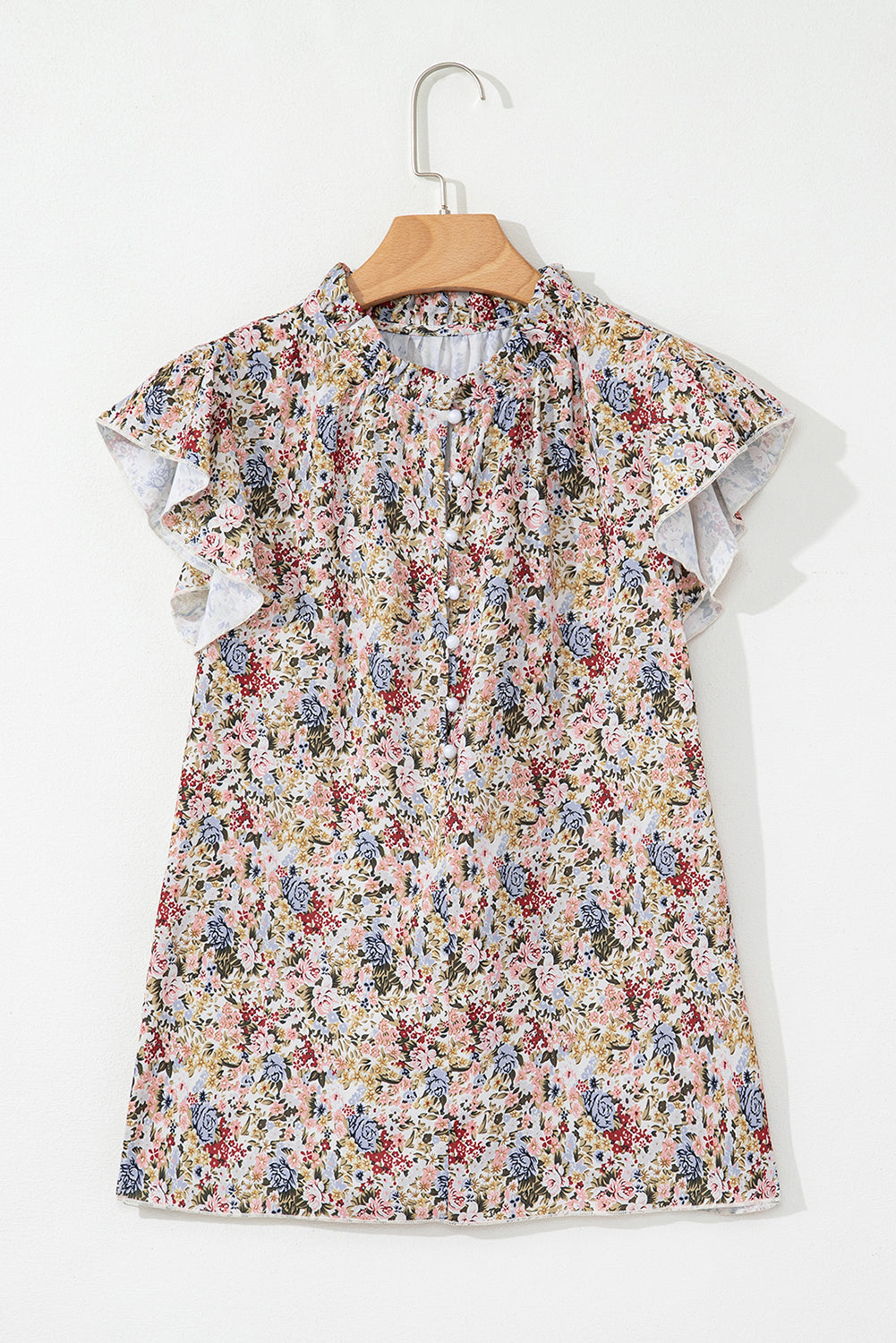 Floral top with ruffled sleeves on a hanger against a white background