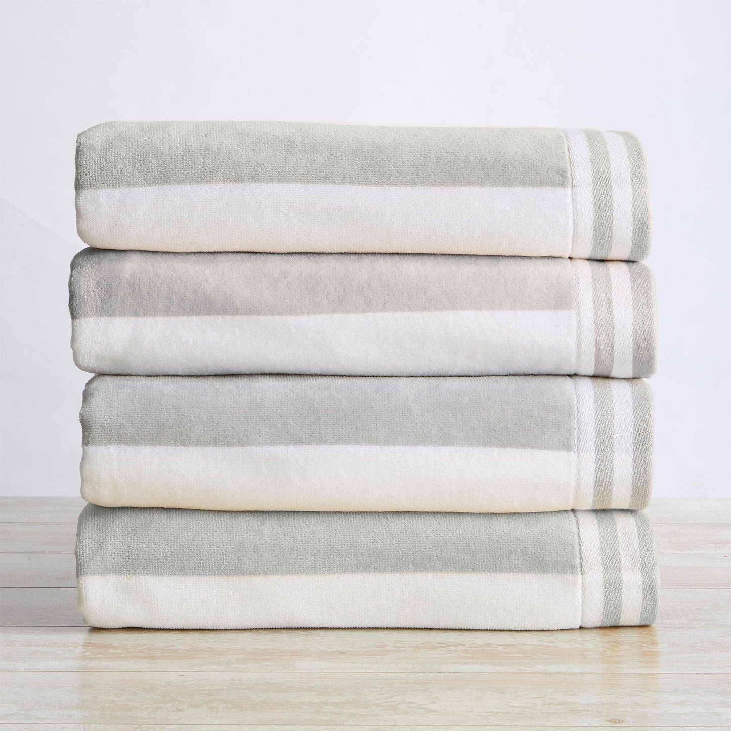 Stack of folded gray and white striped towels on a light wooden surface with a light gray background