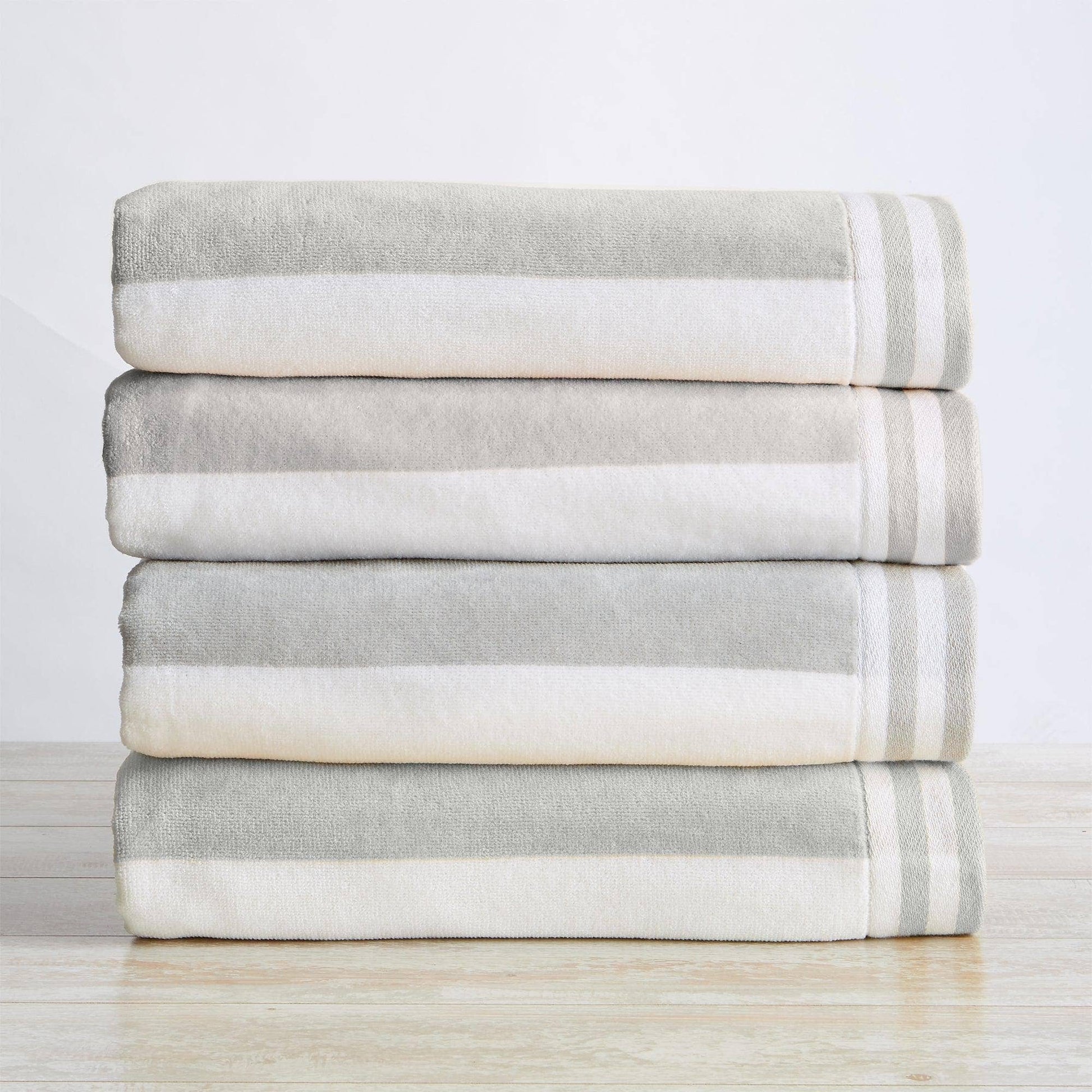 Stack of folded gray and white striped towels on a light wooden surface with a light gray background
