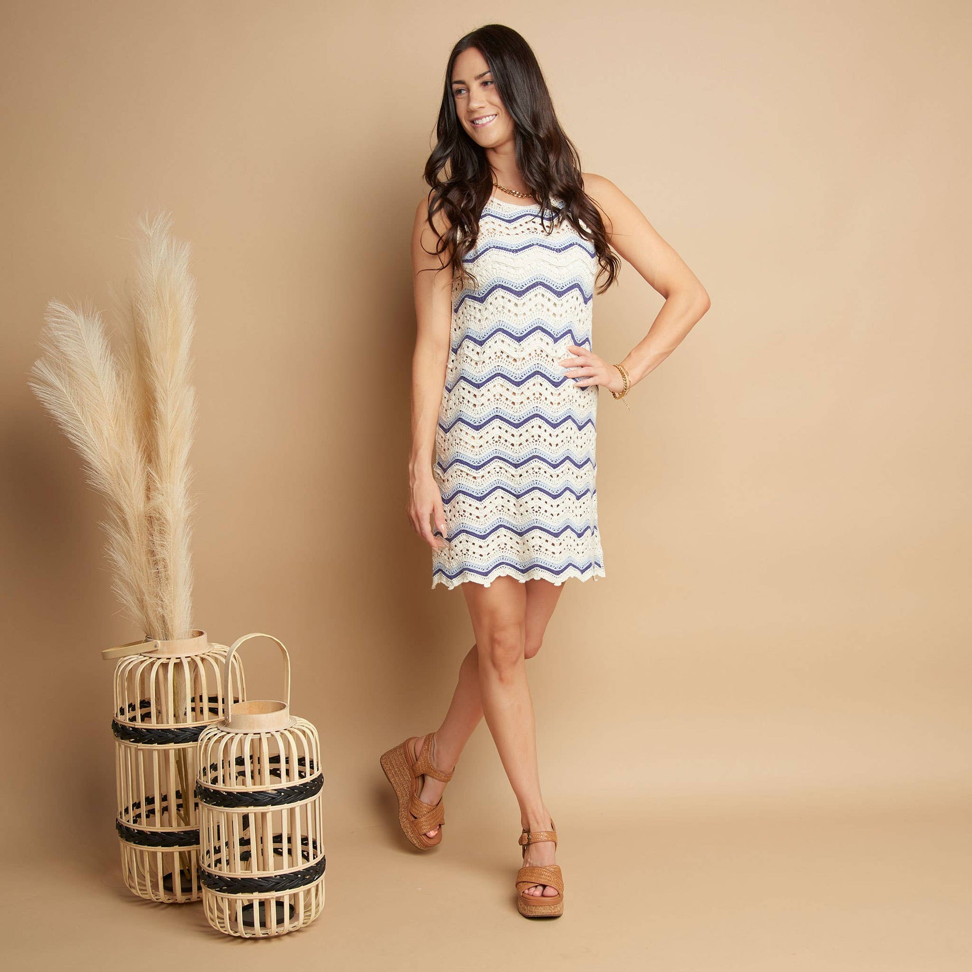 Woman wearing a patterned dress standing next to decorative lanterns on a beige background