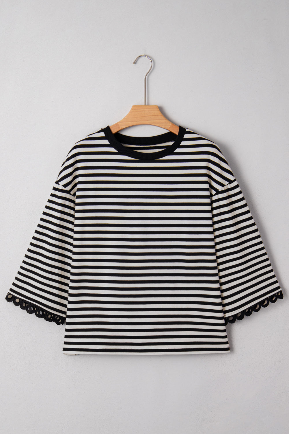 Black and white striped shirt on a hanger against a gray background