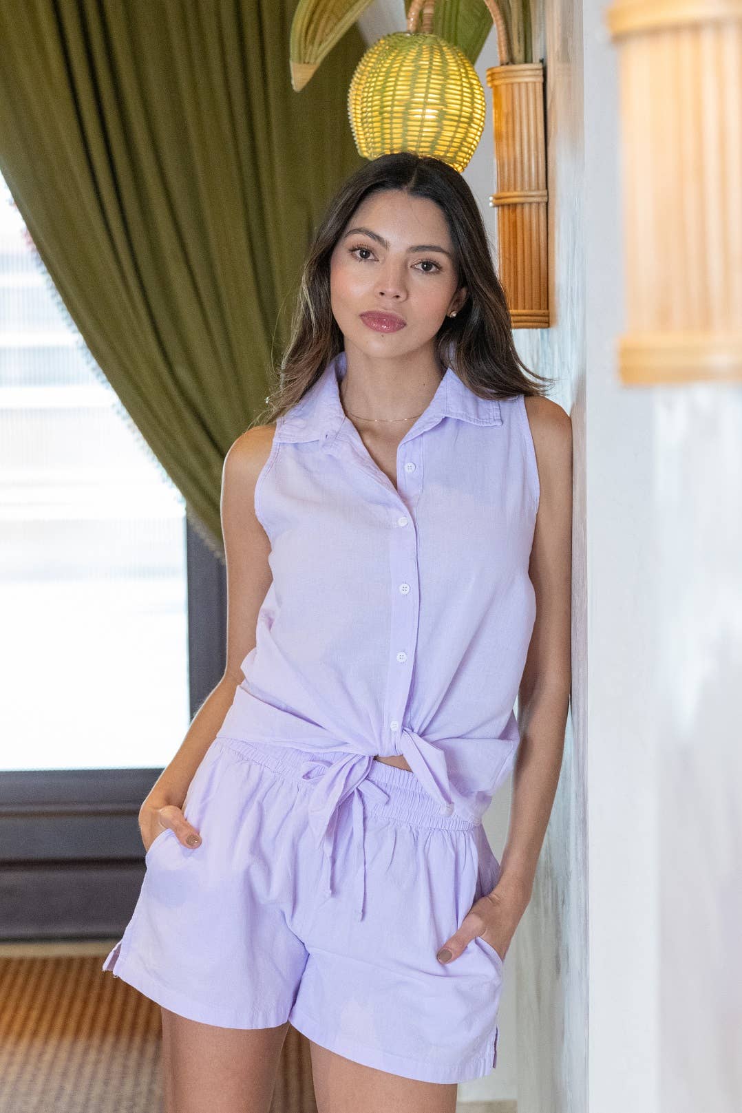 Woman wearing a light purple sleeveless top and shorts set indoors.