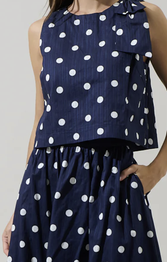 Navy blue skirt with white polka dots worn by a person on a plain background