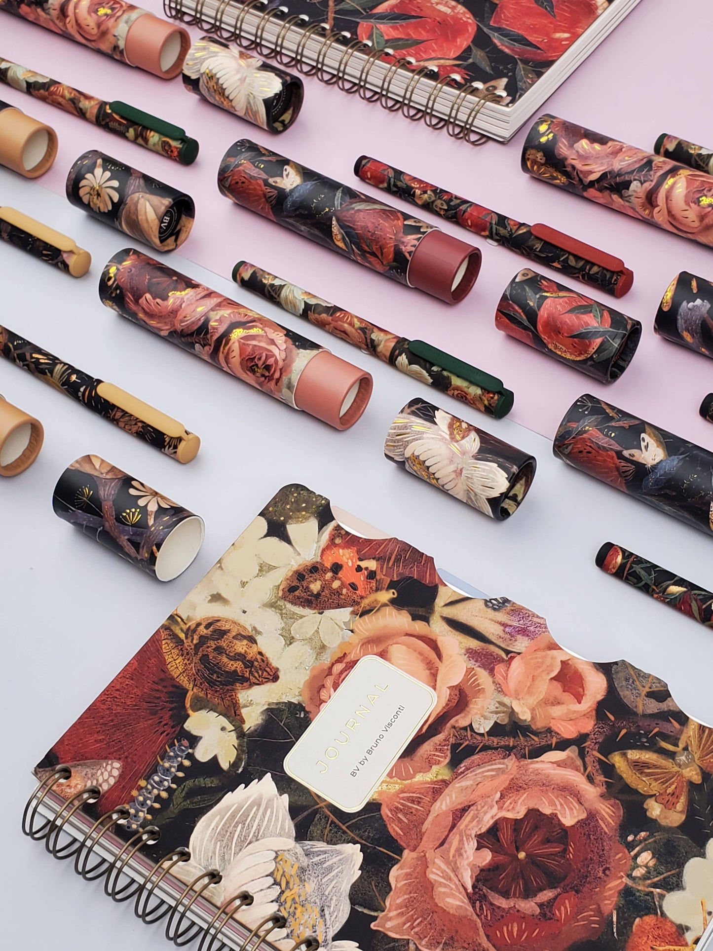 Floral-patterned notebooks and stationery items on a light pink background