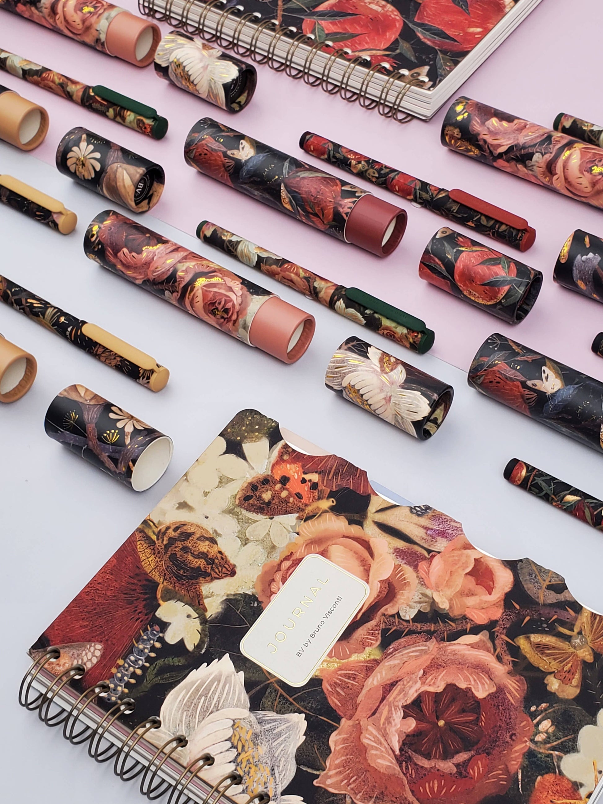 Floral-patterned notebooks and stationery items on a light pink background