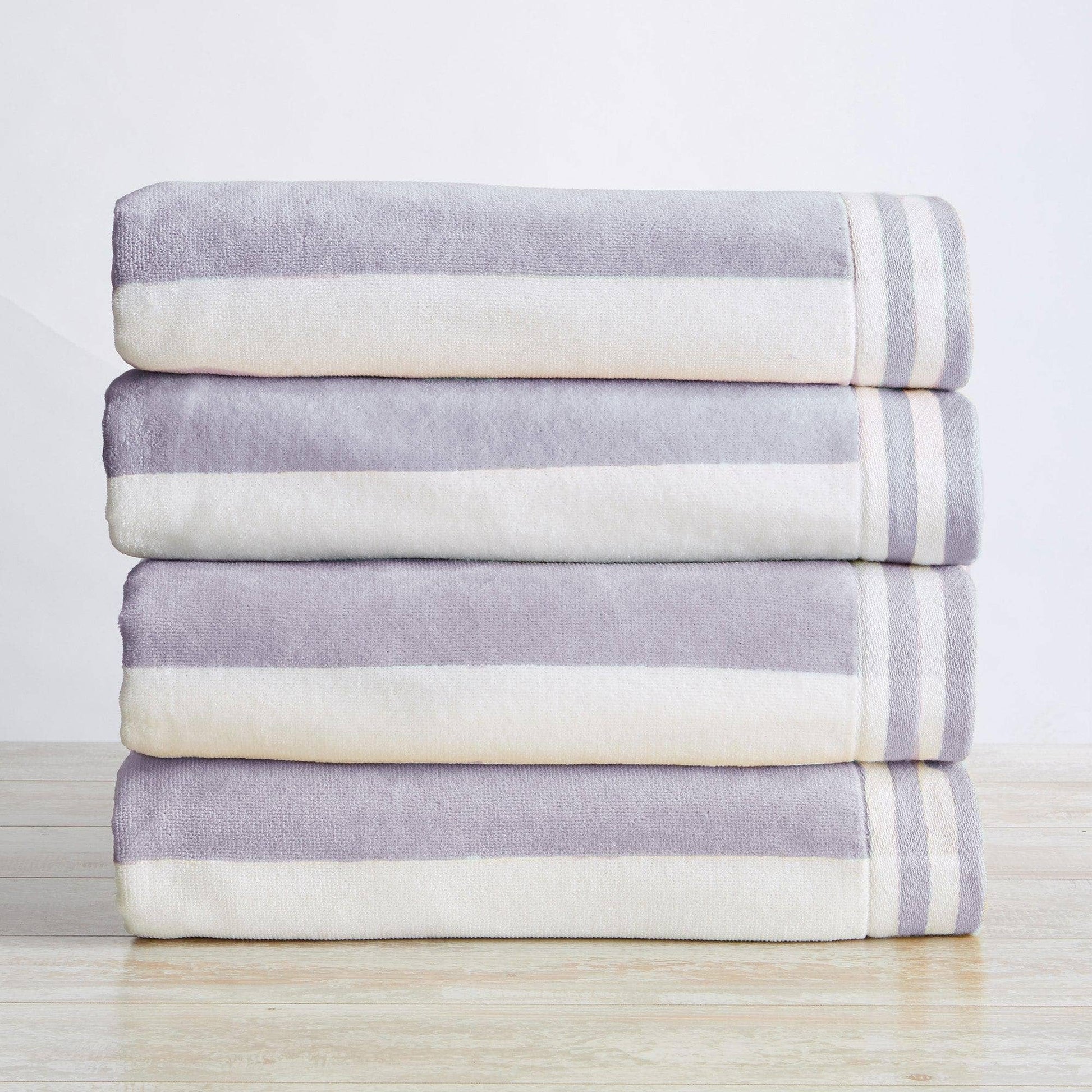 Stack of folded purple and white striped towels on a light wooden surface with a neutral background