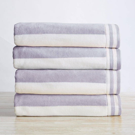 Stack of folded purple and white striped towels on a light wooden surface with a neutral background