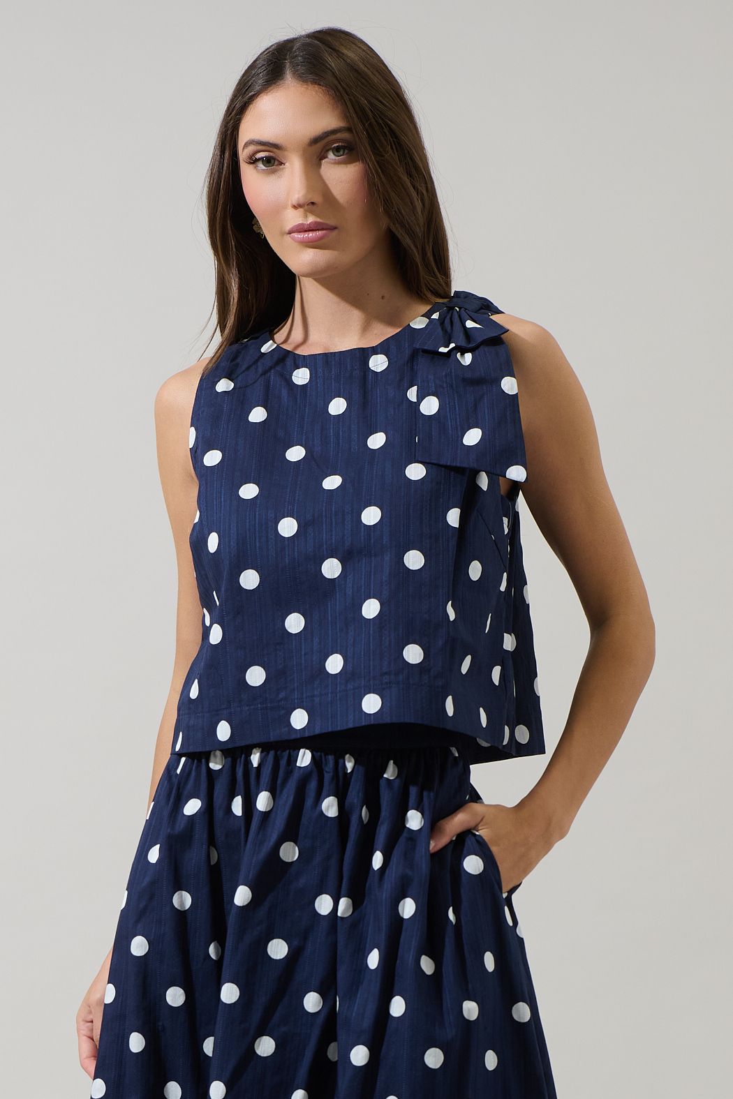 Navy blue skirt with white polka dots worn by a person on a plain background