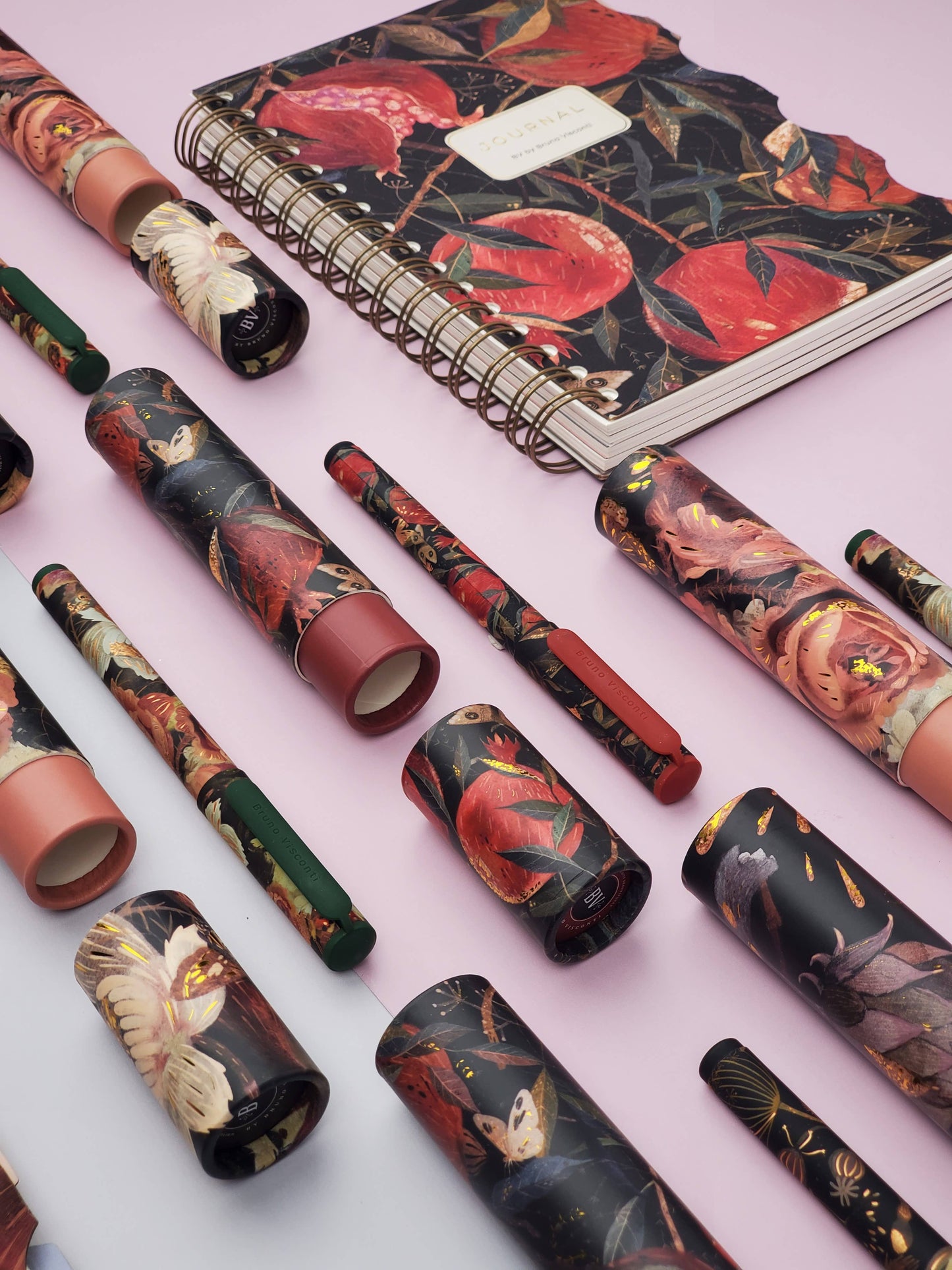 Set of floral-patterned pens and a notebook on a light pink background